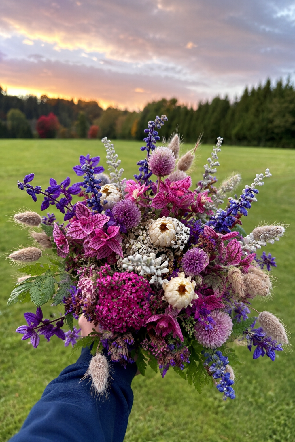 Üppiger Gartenstrauß in Pink, Violett und Weiß vor einer Wiese im Abendlicht