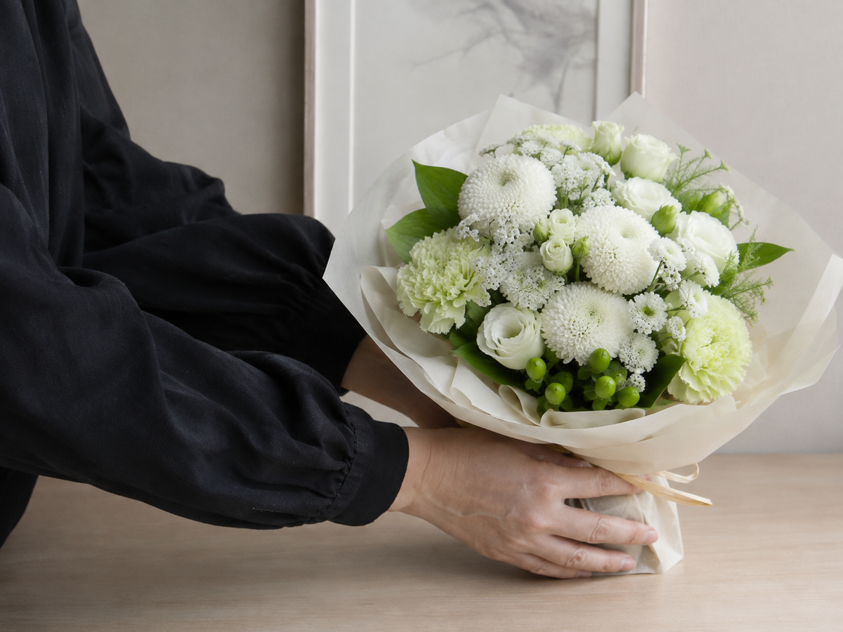 White and green bouquet held by a person dressed in black