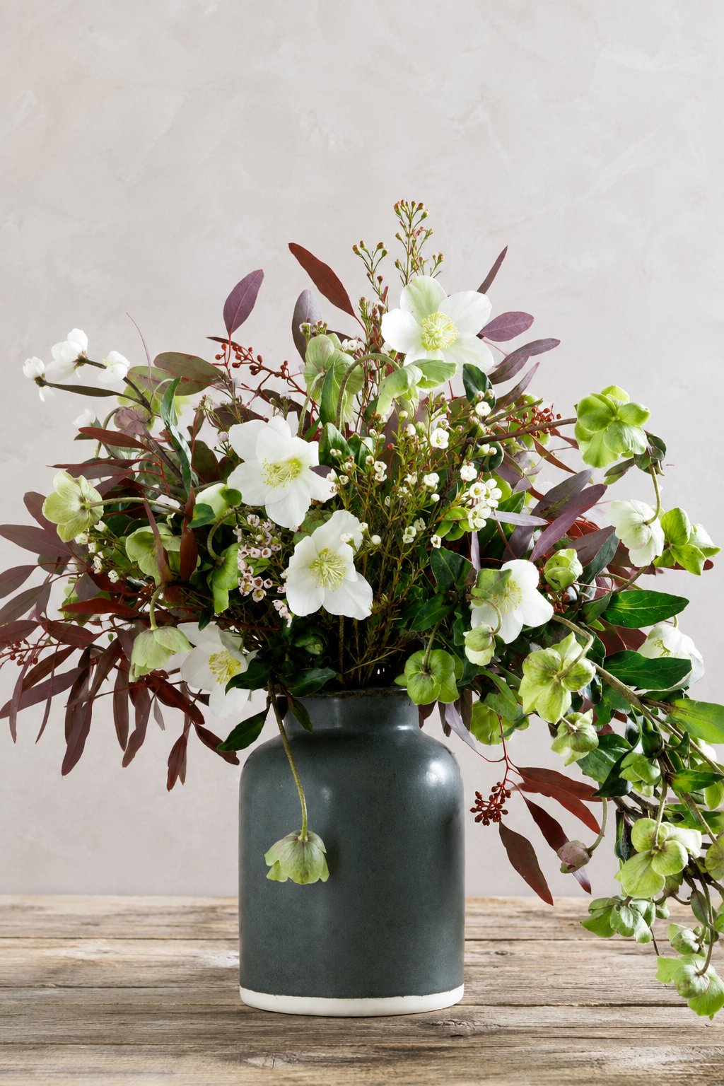 Weiß-grüner Blumenstrauß in einer dunklen Keramikvase