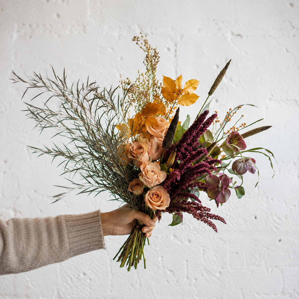 Locker gebundener Herbststrauß mit apricotfarbenen Rosen, Gräsern und dunklen Blüten